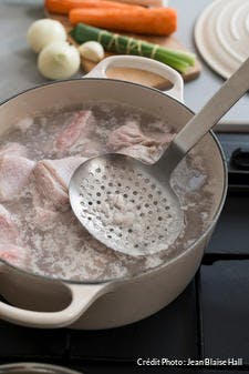 Écumer le bouillon de la blanquette de veau 